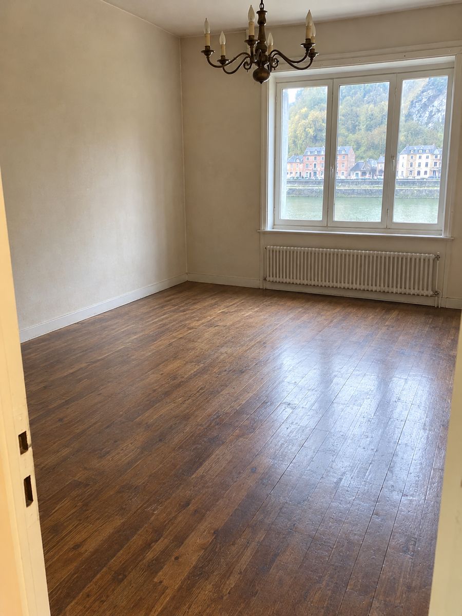 Le même séjour vidé, parquet dégagé et lumière de la fenêtre sur des murs nus