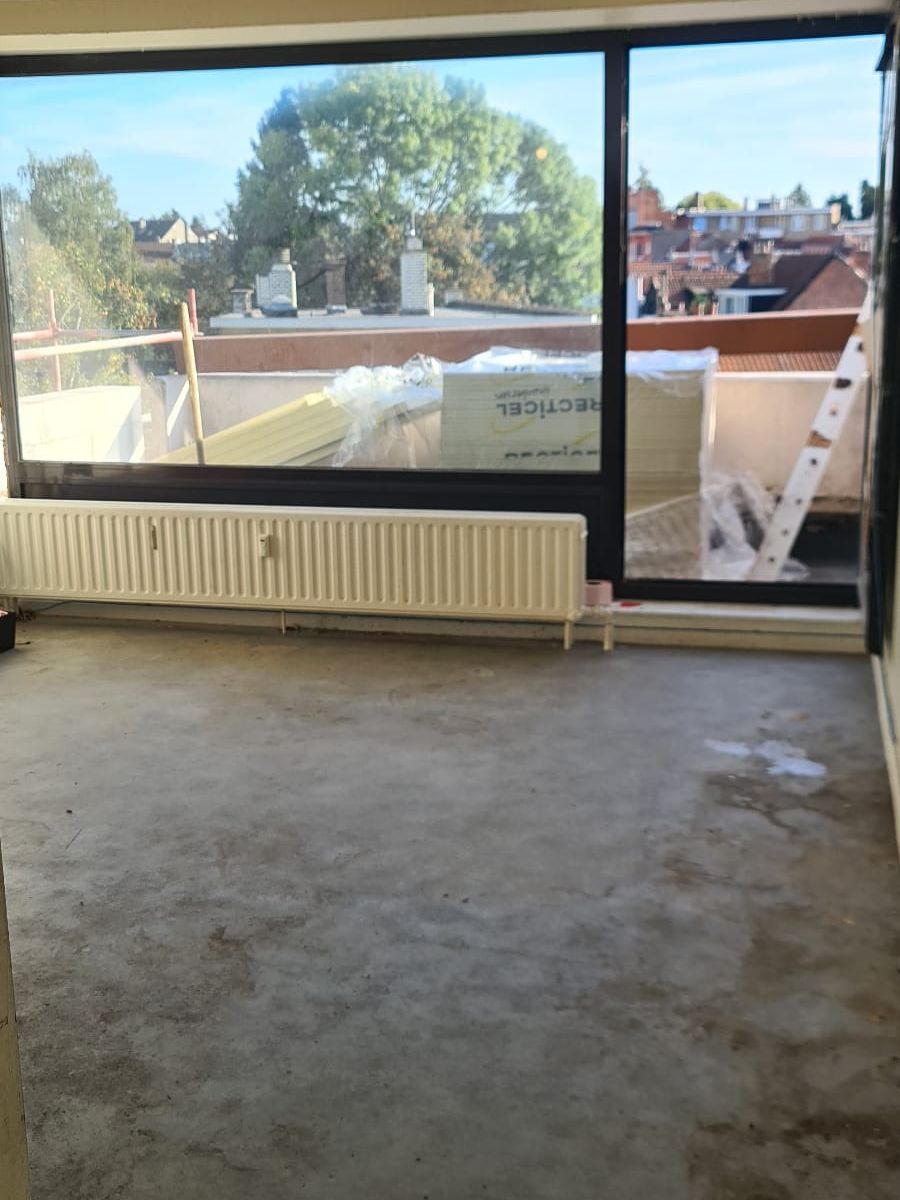 Séjour d’un appartement à Liège entièrement vidé et balayé après notre intervention, baie vitrée ouverte sur la terrasse